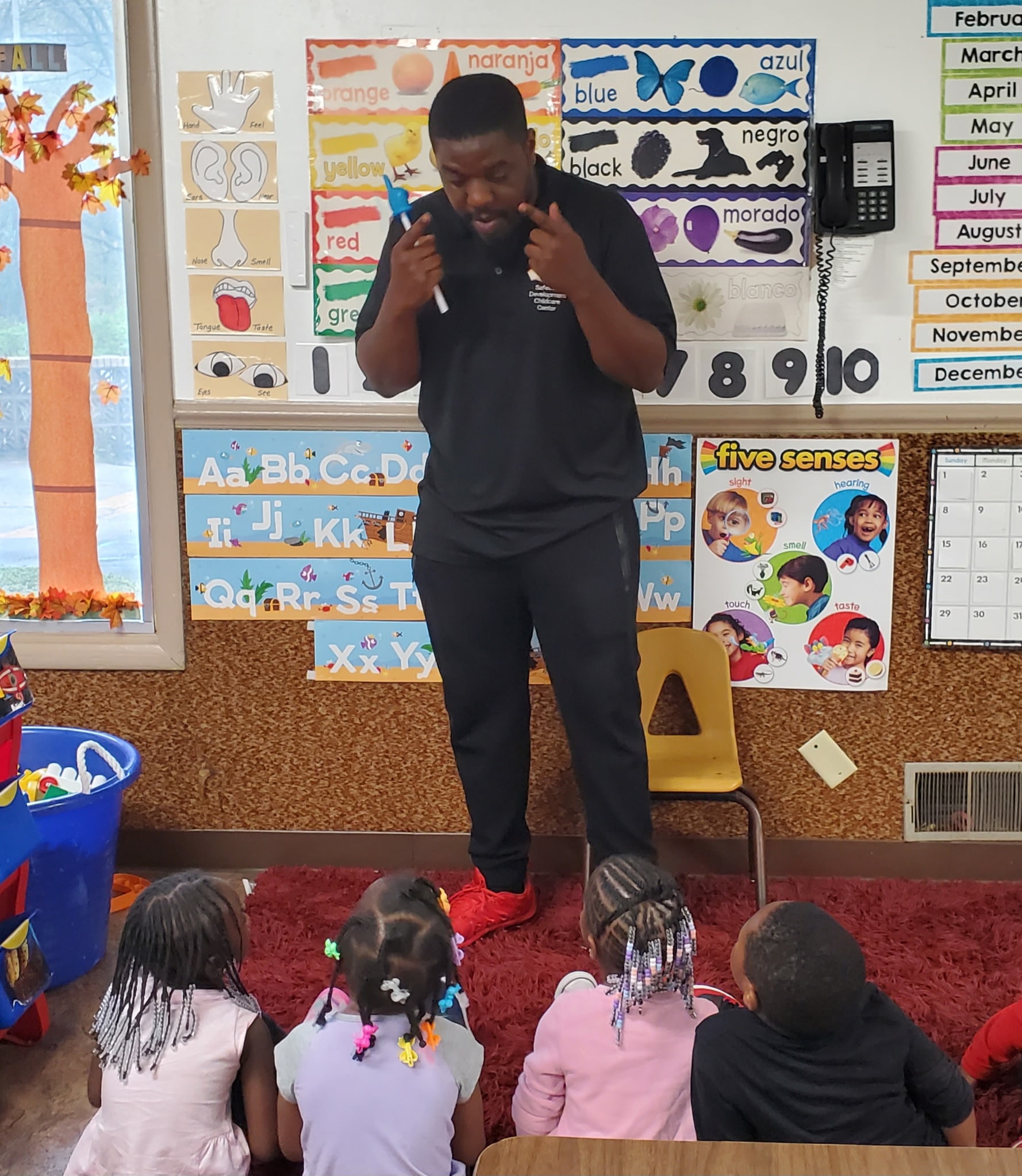 Instructor engaging with students in a colorful classroom filled with educational posters