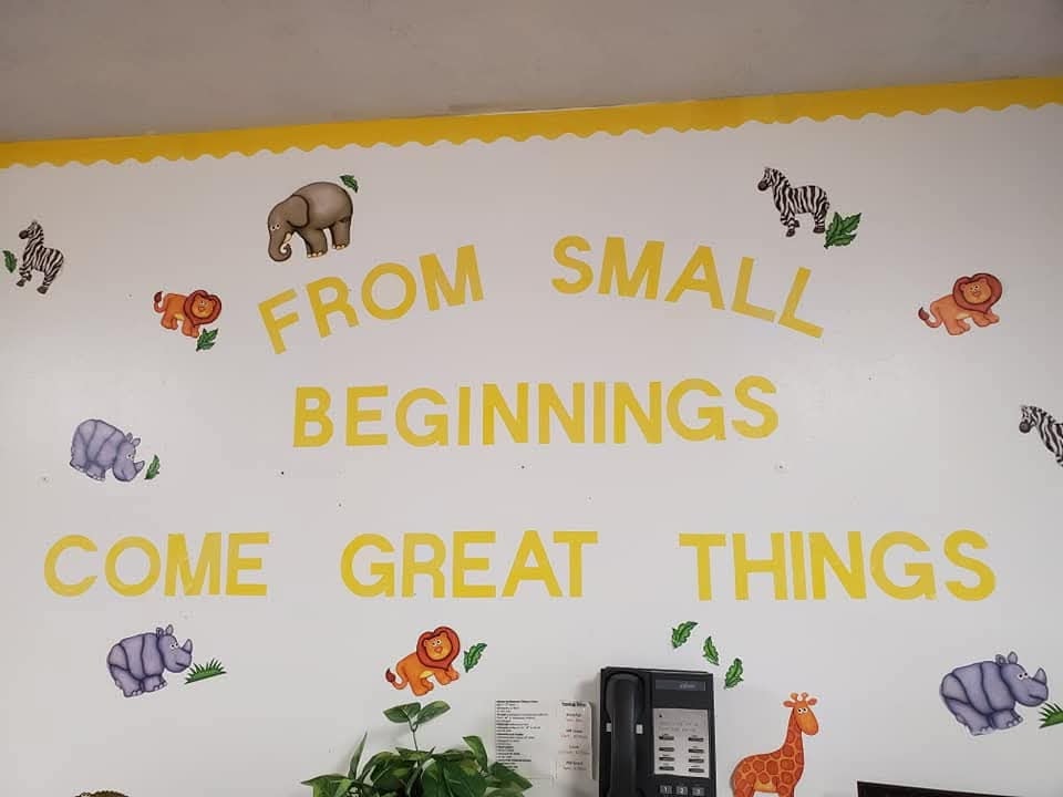 Hallway wall mural reading 'From Small Beginnings Come Great Things' with animal illustrations