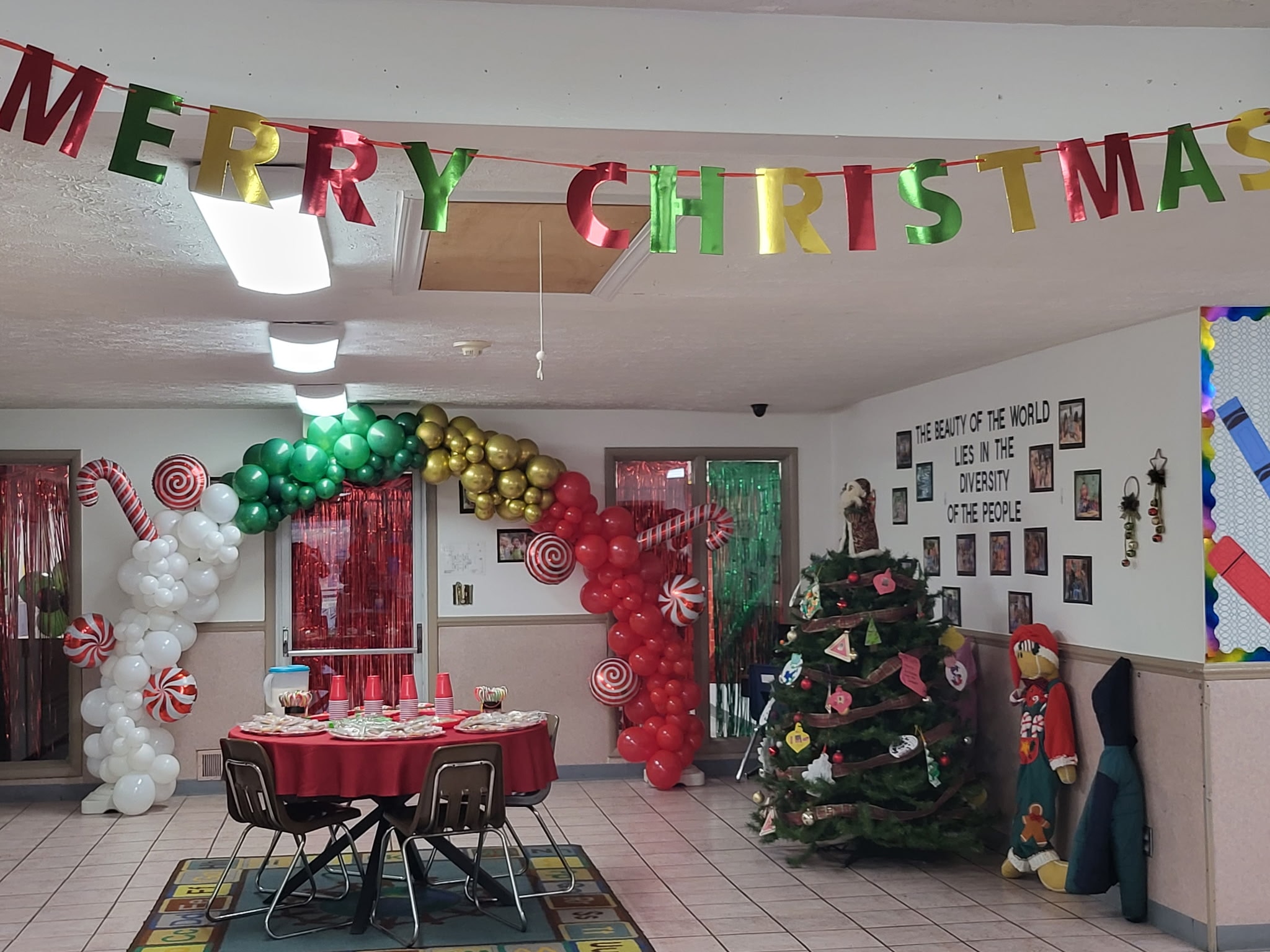 Safecare center decorated for Christmas with balloon arch, candy cane columns, and a Merry Christmas banner