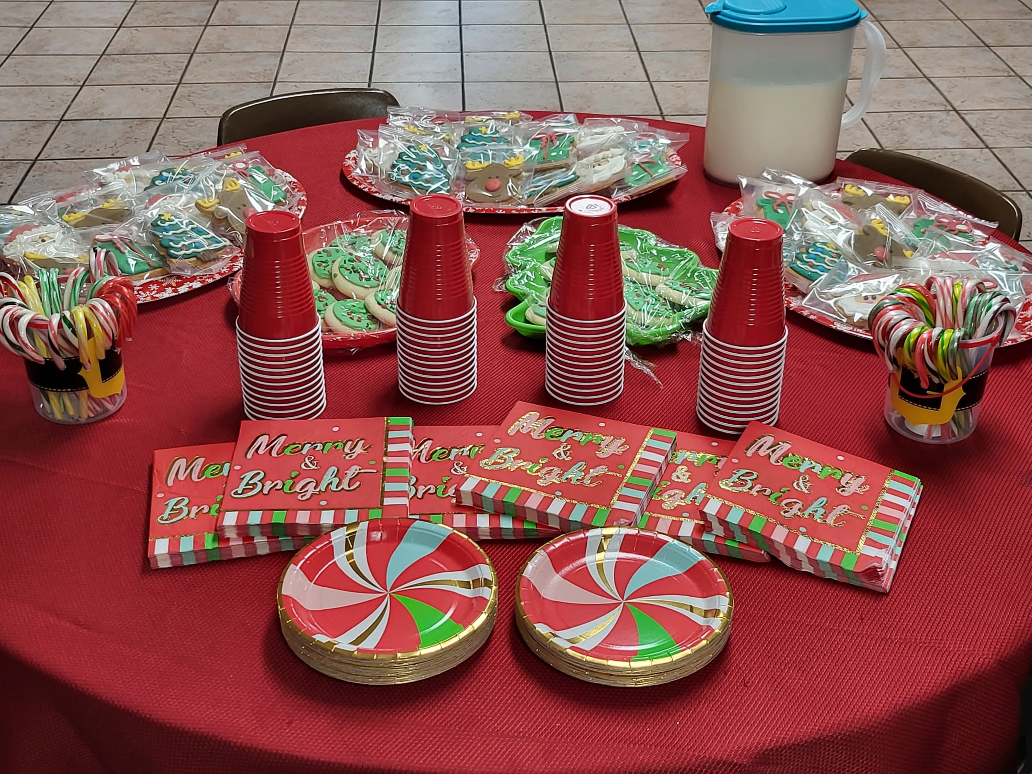 Holiday treat table with decorated cookies, candy canes, and Merry and Bright plates